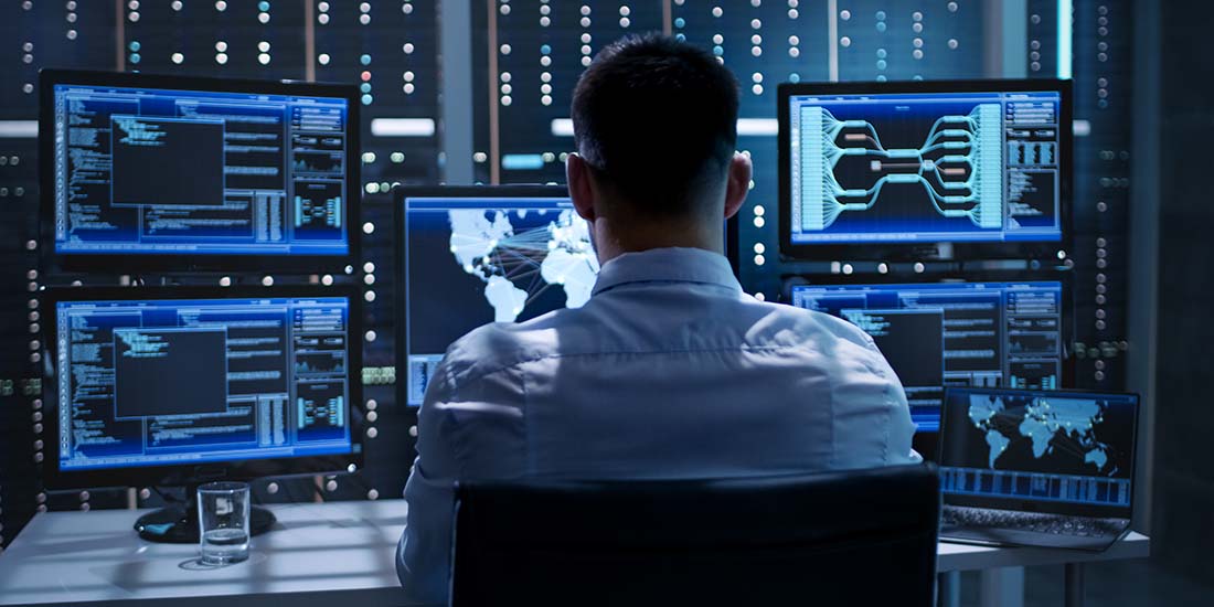 System Security Specialist Working at System Control Center. Roo System Security Specialist Working at System Control Center. Room is Full of Screens Displaying Various Information.